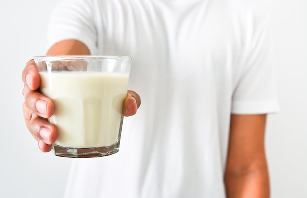Feche a mão do homem segurando um copo de leite no conceito de cuidados de saúde de fundo branco