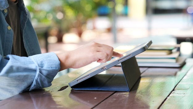 Feche a mão do homem usando o tablet digital para estudo on-line, telecomunicações