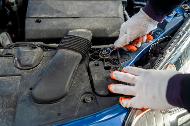 Feche a mão do mecânico usando chave inglesa para reparar o carro ou verificar o motor no capô aberto