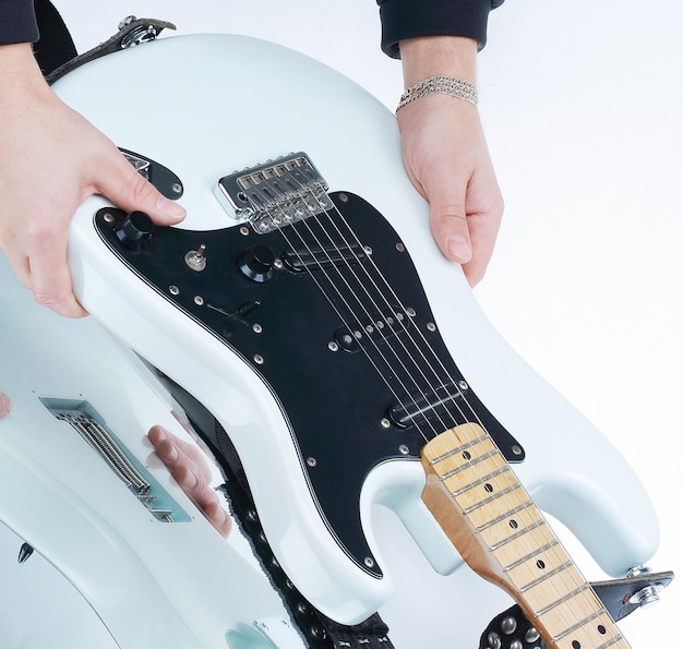 Feche a mão do músico acariciando as cordas de uma guitarra