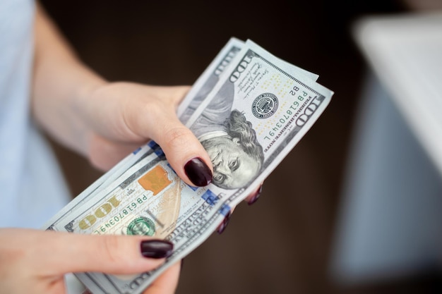 Feche a mão feminina contando e segurando dinheiro dólar americano. conceito de negócios financeiros e crise