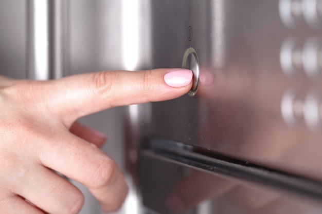 Feche a mão feminina enquanto estiver usando o microondas em sua cozinha