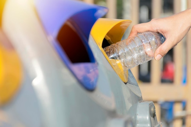 Feche a mão jogando a garrafa de plástico vazia no lixo Conceito de Reciclagem Descarte os resíduos recicláveis para poder reutilizar