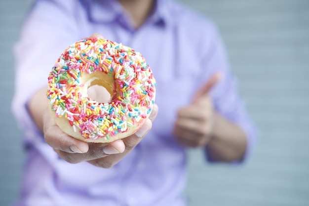 Feche a mão segurando donuts