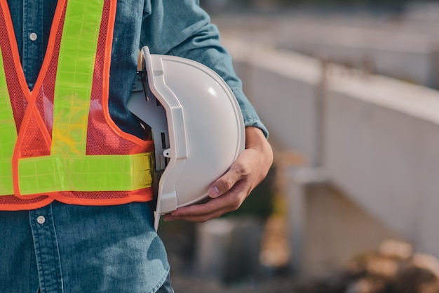 Foto feche a mão segurando o capacete capacete engenheiro civil, contramestre profissional de trabalho