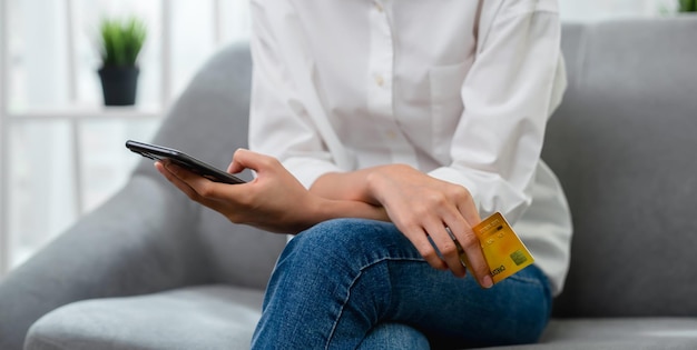 Feche a mão segurando o cartão de crédito com pagamento on-line no smartphone na loja da internet