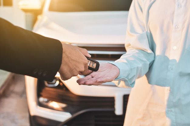 Feche a mão segurando o conceito de carro de venda-chave, dar e receber o carro-chave