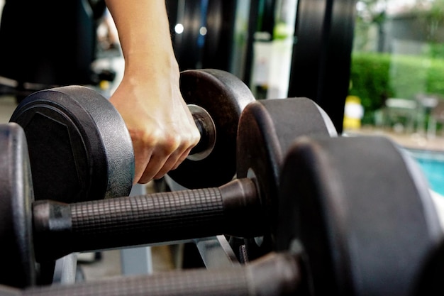 Feche a mão segurando o haltere em fitness. Conceito de exercício e cuidados de saúde.