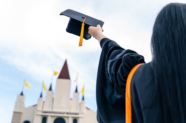 Feche a mão segurando um chapéu de formatura