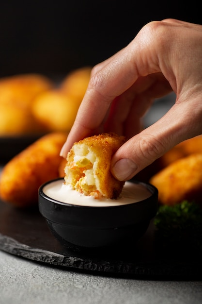 Foto feche a mão segurando um croquete de comida