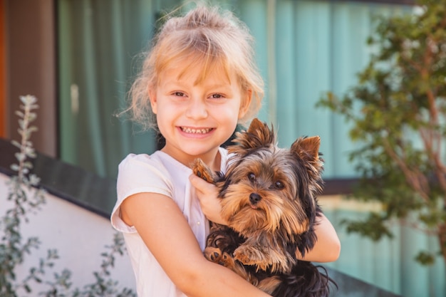 Feche a menina segurando um animal de estimação. Menina segurando um cachorro