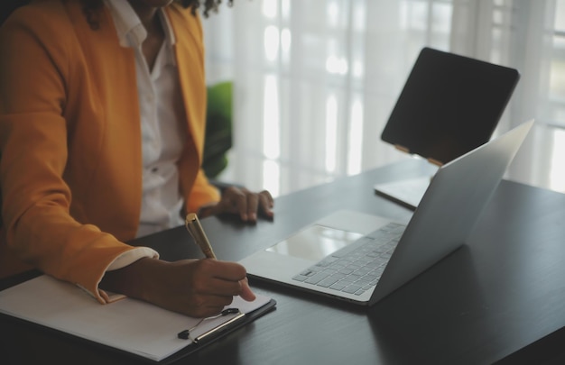 Feche a mulher de negócios usando calculadora e laptop para fazer finanças matemáticas em estatísticas de contabilidade fiscal de mesa de madeira e conceito de pesquisa analítica