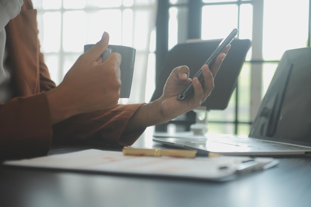 Feche a mulher de negócios usando calculadora e laptop para fazer finanças matemáticas em estatísticas de contabilidade fiscal de mesa de madeira e conceito de pesquisa analítica