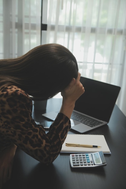 Foto feche a mulher de negócios usando calculadora e laptop para fazer finanças matemáticas em estatísticas de contabilidade fiscal de mesa de madeira e conceito de pesquisa analítica