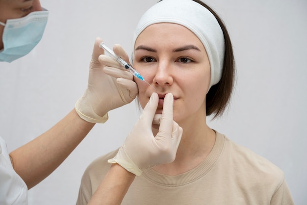 Foto feche a mulher durante o procedimento de preenchimento labial