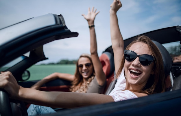 Foto feche a mulher feliz dirigindo um conversívela liberdade da estrada aberta