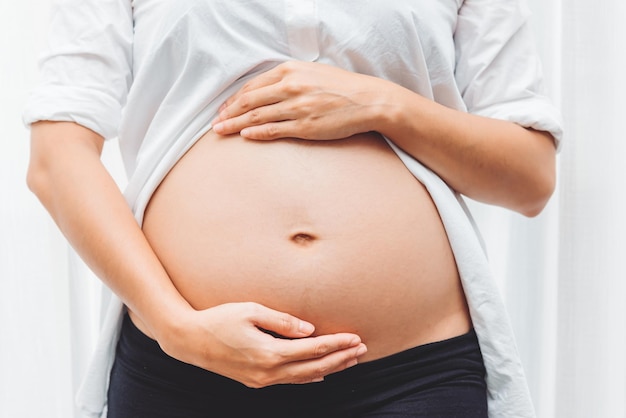 Feche a mulher grávida tocando sua barriga com amor em casa