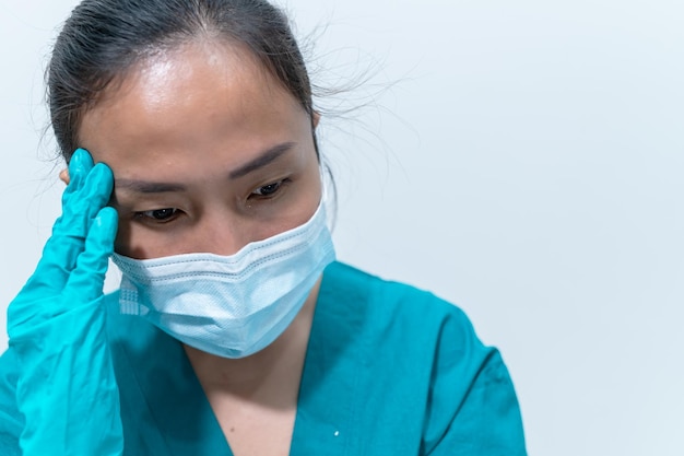 Feche a mulher médica asiática usando máscara para proteger o vírus covid19Ela está muito triste e estressada com o trabalho