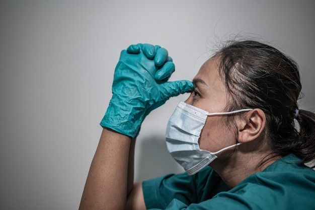 Feche a mulher médica asiática usando máscara para proteger o vírus covid19Ela está muito triste e estressada com o trabalho