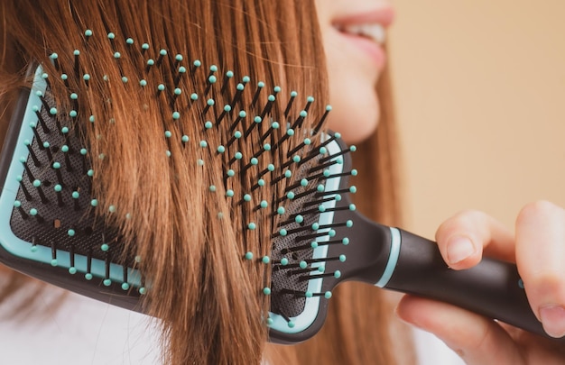 Feche a mulher sorridente, escovando o cabelo com pente linda garota com escova de cabelo comprido