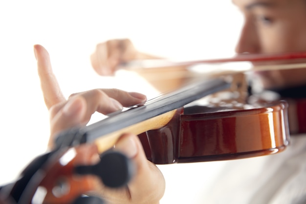 Feche a mulher tocando violino isolado no fundo branco do estúdio. Músico inspirado, detalhes de ocupação artística, instrumento clássico mundial. Conceito de hobby, criatividade, inspiração.