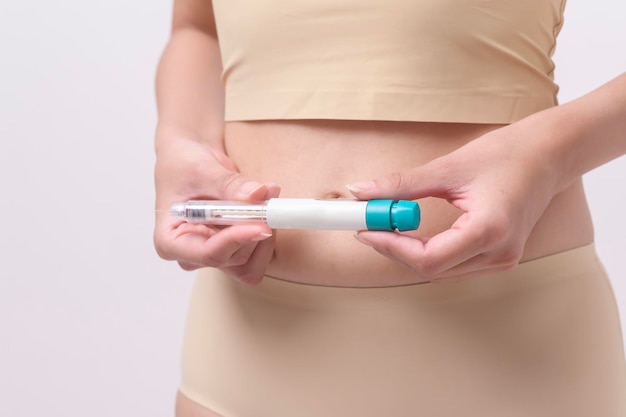 Feche a mulher usando injeção de tratamento de fertilização in vitro na barriga para preparar a fertilidade reprodutiva Ovulação