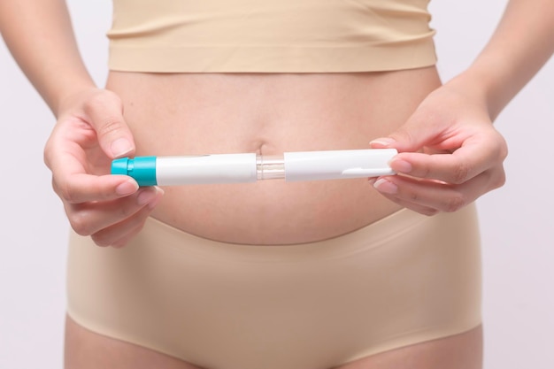 Feche a mulher usando injeção de tratamento de fertilização in vitro na barriga para preparar a fertilidade reprodutiva