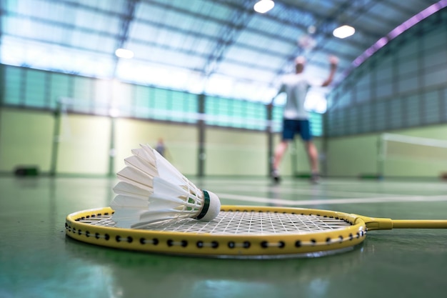 Foto feche a peteca na raquete de badminton em quadras com jogadores competindo