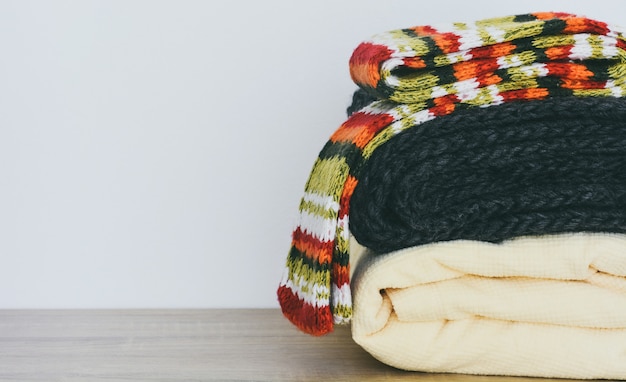 Feche a pilha de roupas de inverno dobradas na mesa de madeira com espaço de cópia de fundo branco