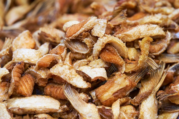 Feche a pilha do mercado de comida de rua tailandesa de pele de salmão frito crocante