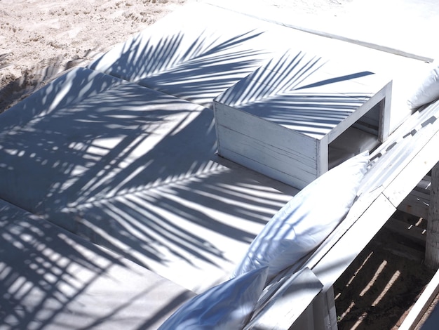 Feche a sombra do padrão de folhas de palmeira na cama de banho de sol na praia de verão.