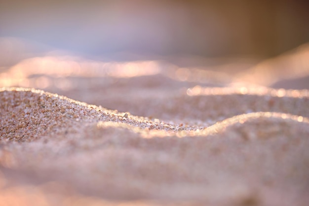 Feche a superfície de areia amarela limpa cobrindo a praia à beira-mar iluminada com luz noturna Conceito de viagem e férias