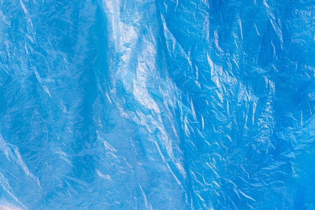 Feche a textura do saco de lixo plástico azul brilhante. Celofane amassado. Fundo de filme de polietileno violeta. Problema de ecologia.
