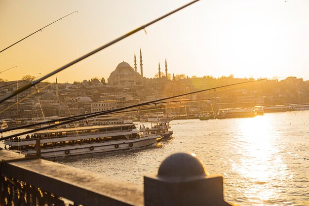 Feche a vista dos pólos de pesca da silhueta de Istambul durante o pôr do sol