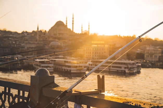 Feche a vista dos pólos de pesca da silhueta de Istambul durante o pôr do sol