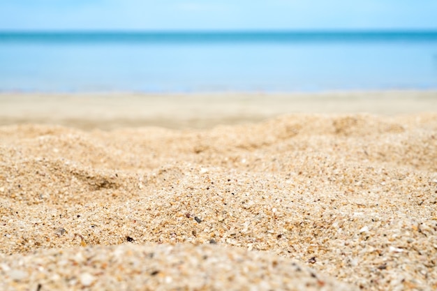 Feche acima da areia da praia com o mar do borrão no fundo