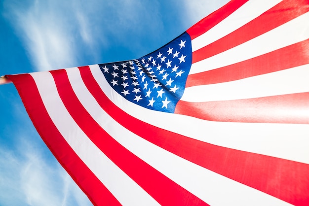 Feche acima da bandeira dos Estados Unidos da América no fundo do céu azul.