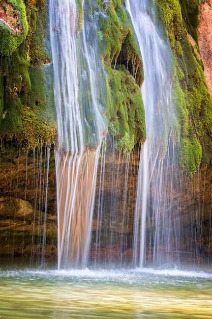 Foto feche acima da cachoeira agradável em rochas cobertas de musgo