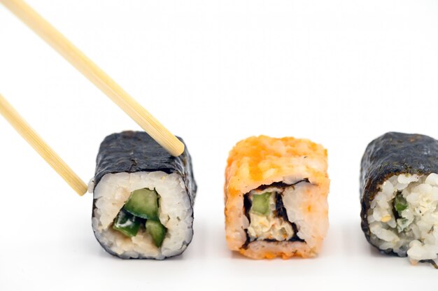 Feche acima da colheita com sushi preparado fresco dos chopsticks no fundo isolado branco.