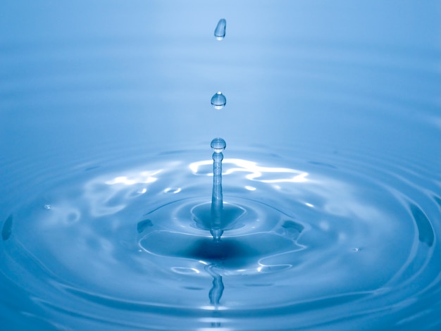 Foto feche acima da gota de água no fundo azul