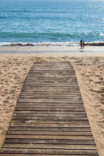 Feche acima da ideia de uma caminhada de madeira da placa na praia que aponta ao mar.