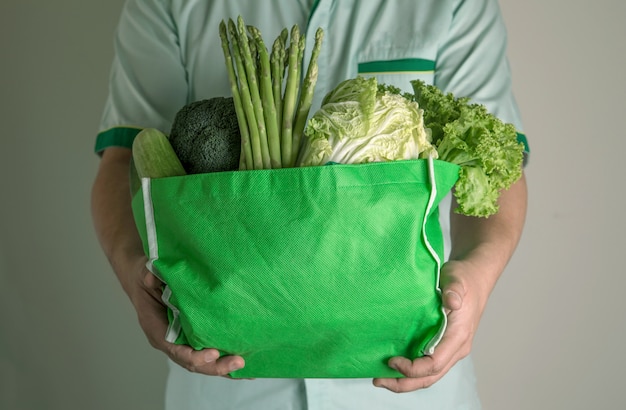 Feche acima da mão segurando sacola verde de misturados os vegetais verdes orgânicos