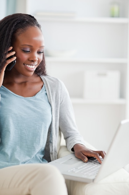 Feche acima da mulher com laptop e smartphone no sofá