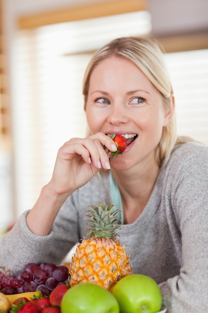 Foto feche acima da mulher comendo um morango