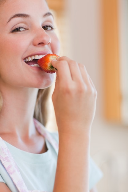 Foto feche acima da mulher comendo um morango