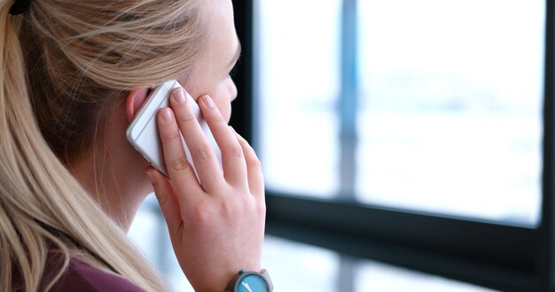 Feche acima da mulher de negócio que usa o telefone celular no interior do escritório