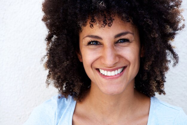 Feche acima da mulher de sorriso com cabelo encaracolado no fundo branco