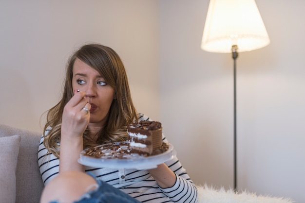 Feche acima da mulher que come o bolo de chocolate.