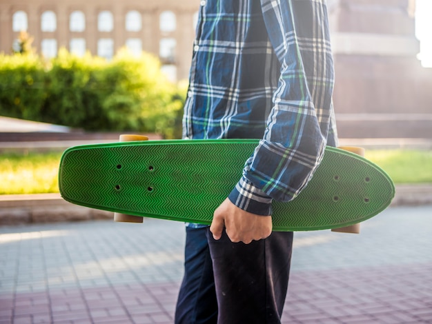 Feche acima da parte do corpo do jovem andando na cidade com moderna nova placa de centavo do skate