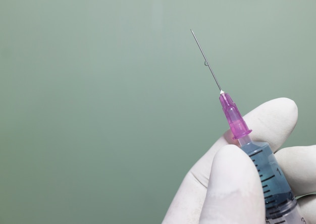 Foto feche acima da seringa nas mãos do doutor na clínica.